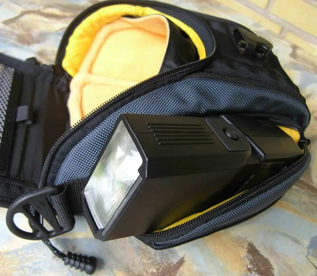 The H-12 is narrower in the buttom than in the top, so it kinda fits the camera with its lens. But there is just enough room for the the flash or a (small) lens in the bottom.